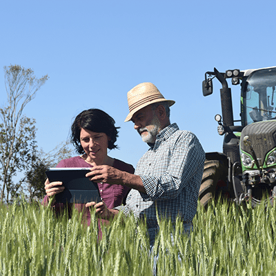 Doi fermieri pe un câmp cu o tabletă digitală.